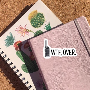 May include: A pink notebook with a black and white sticker of a walkie talkie and the text "WTF, OVER."