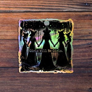 May include: A holographic sticker featuring a silhouette of four witches in a forest setting. The witches are holding hands and the text "Girls Will Be Girls." is printed below them.