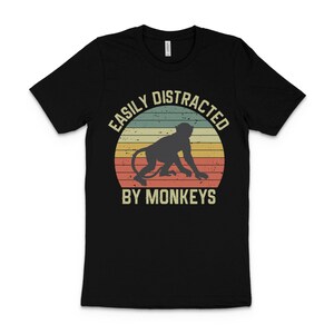 May include: Black t-shirt with a vintage-style graphic of a monkey and the text "Easily Distracted By Monkeys".