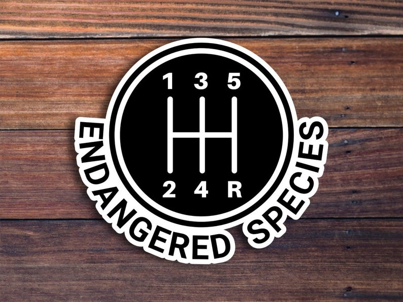 May include: A black and white sticker with a gear shift pattern and the text "ENDANGERED SPECIES" around the outside.