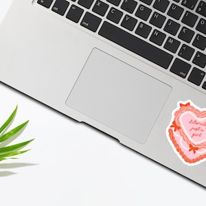 May include: A pink and red heart-shaped sticker with the text "Literally just a girl" on a laptop.