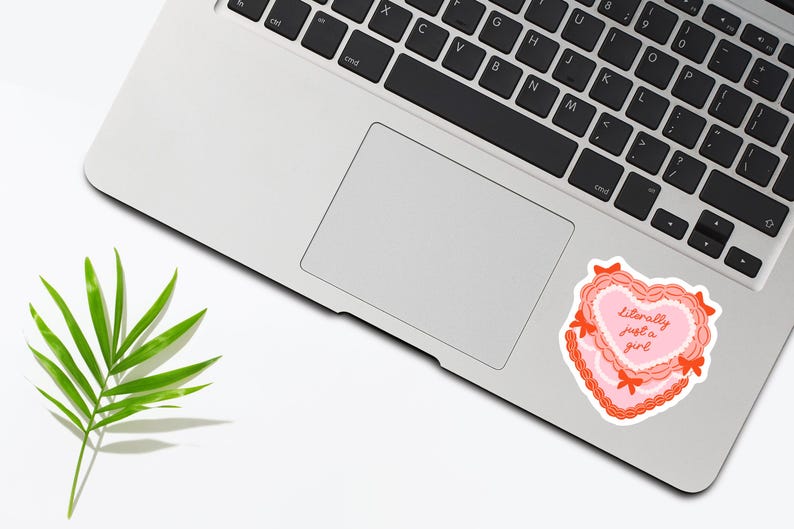May include: A pink and red heart-shaped sticker with the text "Literally just a girl" on a laptop.