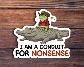 Può includere: Adesivo con un ranocchio dei cartoni animati con un cappello da cowboy e una camicia a quadri rossa, in sella a un alligatore. L'adesivo ha il testo "I AM A CONDUIT FOR NONSENSE" in nero e rosso.