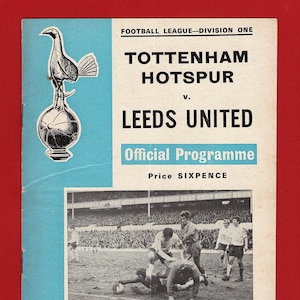 May include: A black and white photo of a soccer game between Tottenham Hotspur and Leeds United. The photo shows a player from Leeds United diving to block a shot from a Tottenham Hotspur player. The game was played on Saturday, February 14, 1970. The program cover is blue and white and features the Tottenham Hotspur crest.
