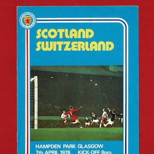 Può includere: Copertina di un programma ufficiale vintage per una partita di calcio Scozia contro Svizzera. La copertina blu presenta "SCOTLAND SWITZERLAND" in giallo, con una scena dello stadio e i dettagli della partita. Il programma è del 7 aprile 1976.