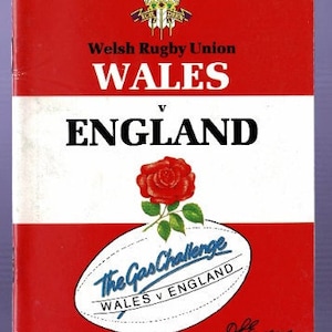 Może przedstawiać: Czerwono-biały program meczu rugby pomiędzy Walią a Anglią. Program zawiera logo Walijskiego Związku Rugby, czerwoną różę i białą piłkę do rugby z tekstem "The Gas Challenge Wales v England". Program jest przeznaczony na mecz, który odbył się w The Cardiff Arms Park w sobotę, 19 stycznia 1991 roku.