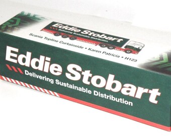 May include: A rectangular box with the words "Eddie Stobart" in large white letters on a dark green background. The box also features the text "Delivering Sustainable Distribution" and a graphic of a truck.