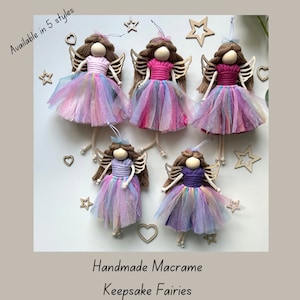 May include: Five handmade macrame fairy ornaments with rainbow tulle skirts and wooden wings. The fairies have brown hair and are wearing pink, purple, and white tops. Available in 5 styles.