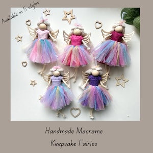 May include: Five handmade macrame fairy ornaments with different coloured yarn and tulle skirts. The fairies are hanging from a white background with wooden stars and hearts.