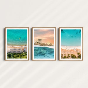 May include: Three framed photographs of a beach scene with turquoise water, white sand, and a small island with a tree. The top of the water is visible in the middle photo, while the bottom of the water is visible in the left and right photos.