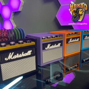 May include: A collection of miniature Marshall amplifier-style containers in black, purple, orange, and blue. Each features the "Marshall" logo and a speaker grill design. One container holds colorful discs.