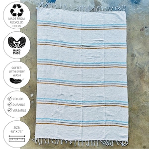 Beach blanket made from upcycled cotton, perfect for beach days, picnics, or yoga. This colorful Mexican blanket is a versatile outdoor blanket, ideal for summer adventures, camping, or as a cozy home decor throw. Soft, lightweight, and eco-friendly, it doubles as a boho throw blanket, blanket gift, or decorative layer for any coastal space. Handwoven by artisans, this sustainable, upcycled cotton blanket adds comfort and style wherever it goes.