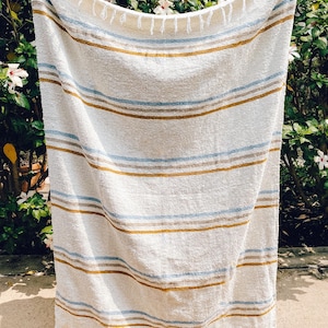 Beach blanket made from upcycled cotton, perfect for beach days, picnics, or yoga. This colorful Mexican blanket is a versatile outdoor blanket, ideal for summer adventures, camping, or as a cozy home decor throw. Soft, lightweight, and eco-friendly, it doubles as a boho throw blanket, blanket gift, or decorative layer for any coastal space. Handwoven by artisans, this sustainable, upcycled cotton blanket adds comfort and style wherever it goes.