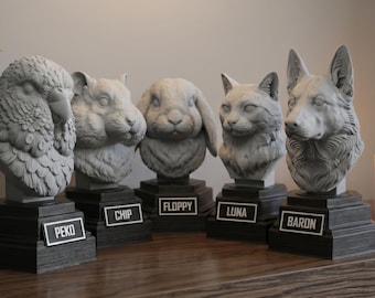 May include: A collection of five gray animal bust sculptures, including an eagle, hamster, rabbit, cat, and wolf. Each bust is mounted on a dark, rectangular base with a nameplate. The sculptures are displayed on a wooden shelf with a plant and candle.