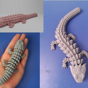 Könnte beinhalten: Ein 3D-gedrucktes Modell einer Eidechse mit einem stacheligen, gepanzerten Körper. Die Eidechse ist grau und hat einen langen Schwanz. Das Modell wird aus verschiedenen Blickwinkeln gezeigt.
