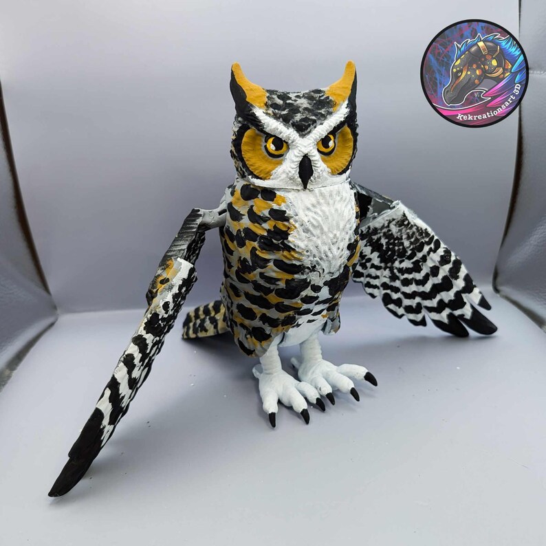 Puede incluir: Una figurita de b&uacute;ho impresa en 3D con plumas negras, blancas y amarillas. El b&uacute;ho tiene una cara blanca con ojos amarillos y un pico negro. El b&uacute;ho est&aacute; de pie sobre una superficie blanca.