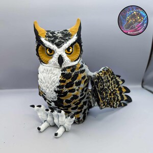 Puede incluir: Una figurita de b&uacute;ho pintada a mano con marcas marrones, negras, blancas y amarillas. El b&uacute;ho est&aacute; posado con las alas extendidas y tiene garras detalladas.