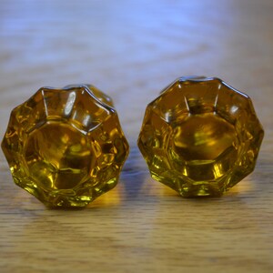 May include: Two amber glass door knobs with a faceted design.