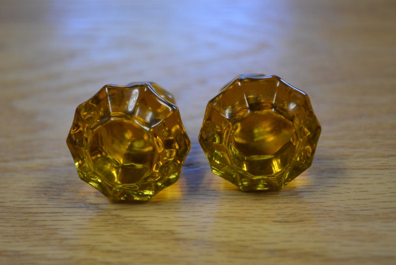 May include: Two amber glass door knobs with a faceted design.
