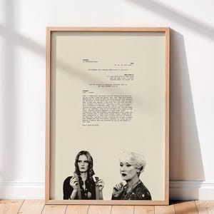 May include: A framed wall art print featuring a beige background with black typewriter-style movie script text and a black and white photograph of two women at the bottom. The text includes dialogue from a scene about a cerulean blue sweater.
