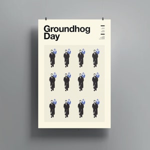 May include: A poster with the text "Groundhog Day" in black text on a white background. The poster features a repeated pattern of a man in a black coat and hat, with a blue silhouette of a groundhog behind him.