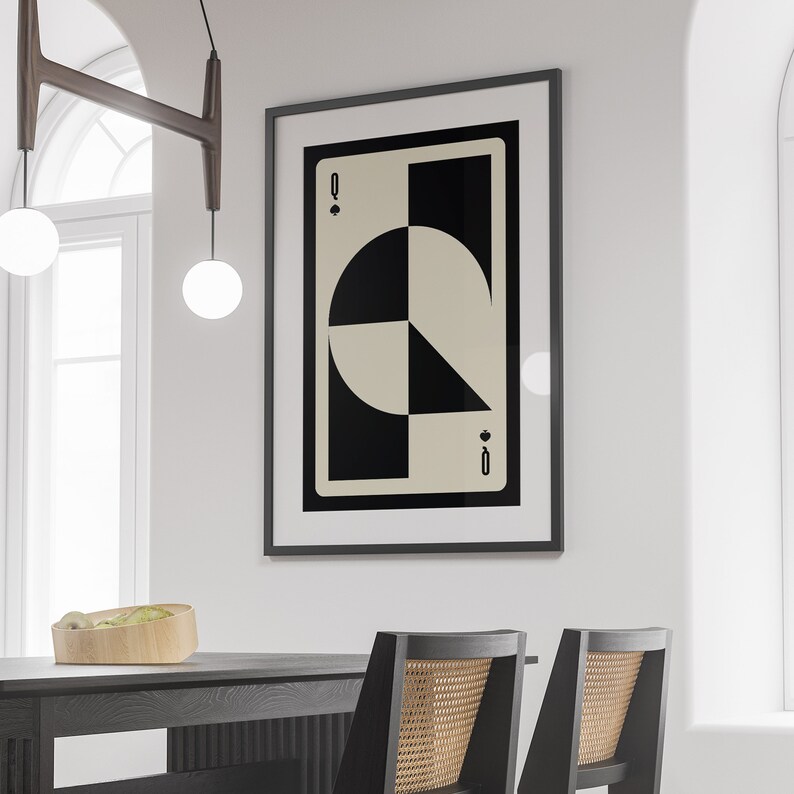 May include: A black framed print of a playing card with a geometric design in black and white. The card is the Queen of Spades.