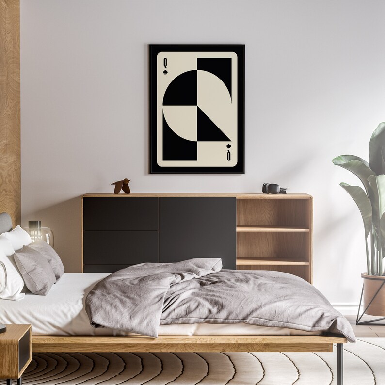 May include: A black and white geometric design of a playing card, the Queen of Diamonds. The card is framed in a black frame and is hanging on a white wall.