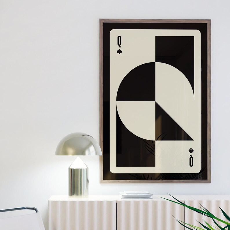 May include: A framed print of a black and white geometric design of the Queen of Spades playing card. The card is framed in a dark wood frame.