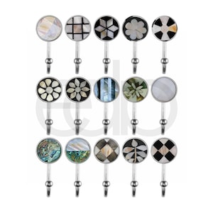 Peut inclure: Une collection de crochets muraux décoratifs avec des faces rondes et à motifs. Les crochets présentent divers motifs, notamment floraux, géométriques et abstraits, avec des accents irisés et noir et blanc. Chaque crochet a une base en métal argenté.
