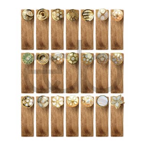 May include: A collection of decorative cabinet knobs with various designs. Each knob is mounted on a rectangular wooden base. The knobs feature gold, mother-of-pearl, and other decorative elements. The designs include floral, geometric, and circular patterns.