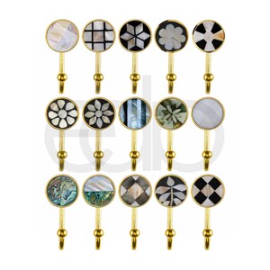 May include: A selection of decorative wall hooks with circular, inlaid designs. The hooks have a gold-coloured metal base and various patterns, including floral and geometric. The inlaid designs feature mother-of-pearl and other materials, adding a touch of elegance.