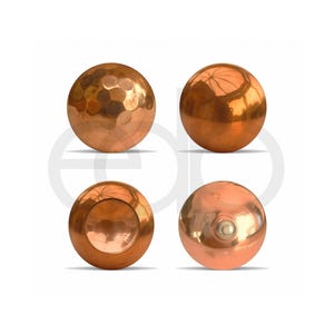 May include: Four copper spheres with different surface textures and finishes. One sphere has a hammered, dimpled pattern, while others are smooth and reflective. The spheres are a warm, metallic colour, and are displayed against a white background.