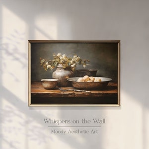 May include: A still life painting depicting a wooden table with a silver vase filled with white flowers, a bowl of potatoes, and three silver bowls. The painting is framed in a gold frame and has the text "Whispers on the Wall" and "Moody Aesthetic Art" below the image.