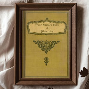 May include: A framed print with a vintage aesthetic. The print features a yellow background with green floral designs and the text "(Your Name)'s Book of White Lies".