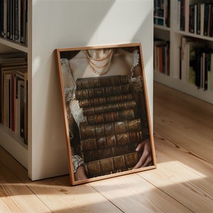 May include: A framed print of a woman wearing a white dress and a pearl necklace, holding a stack of antique books in front of her chest.
