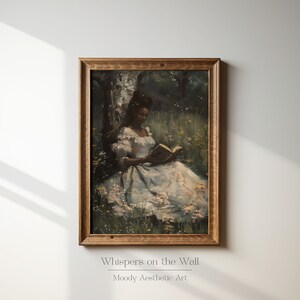 May include: A framed painting of a woman in a white dress sitting in a field of flowers and reading a book. The painting is in a wooden frame and has a vintage aesthetic.