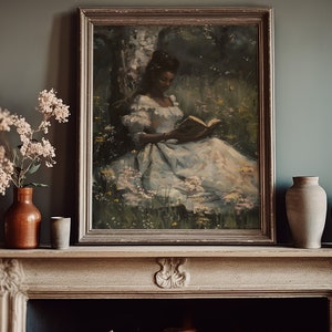 May include: A framed painting of a woman in a white dress reading a book in a forest setting. The painting is in a dark wood frame and is hanging on a wall above a fireplace.