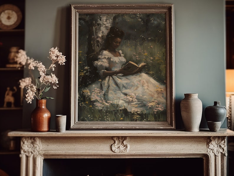 May include: A framed painting of a woman in a white dress reading a book in a forest setting. The painting is in a dark wood frame and is hanging on a wall above a fireplace.