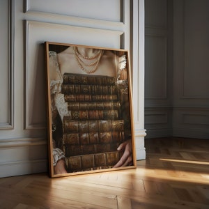 May include: A framed print of a woman wearing a pearl necklace and holding a stack of antique books in front of her chest.