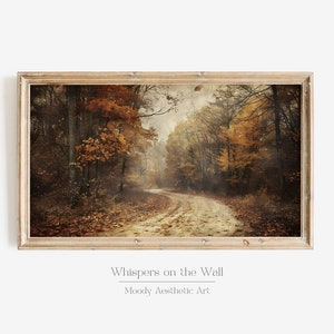 May include: A framed print showcases an autumnal forest scene with a winding road. The trees are adorned with orange and yellow leaves. The print is set in a light wood frame. Text at the bottom reads "Whispers on the Wall" and "Moody Aesthetic Art."