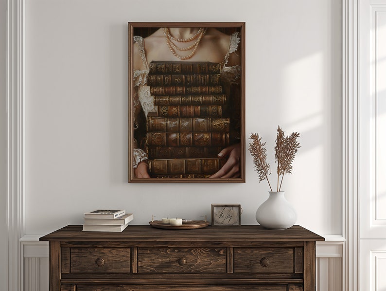 May include: A framed portrait of a woman wearing a pearl necklace and holding a stack of antique books in front of her chest.