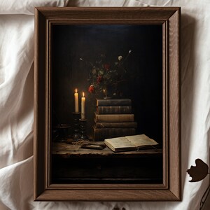 Peut inclure: Une photographie encadr&eacute;e d'une nature morte avec une pile de livres, deux bougies allum&eacute;es et un vase de fleurs sur une table en bois.