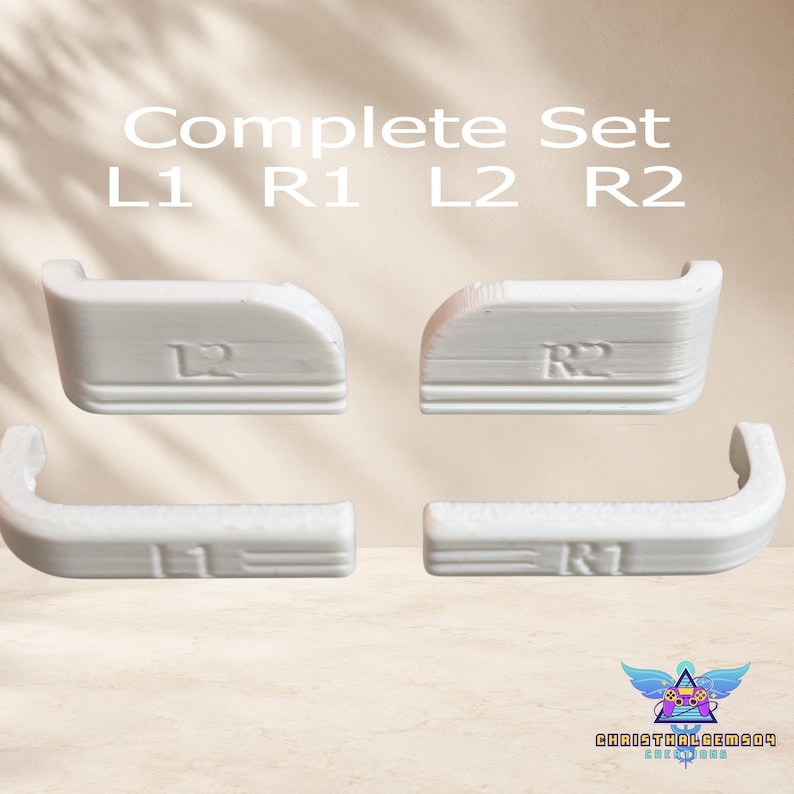 May include: A complete set of four white replacement controller shoulder buttons labeled L1, R1, L2, and R2. The components feature a textured, layered finish consistent with 3D printing, with the text Complete Set L1 R1 L2 R2 visible above.