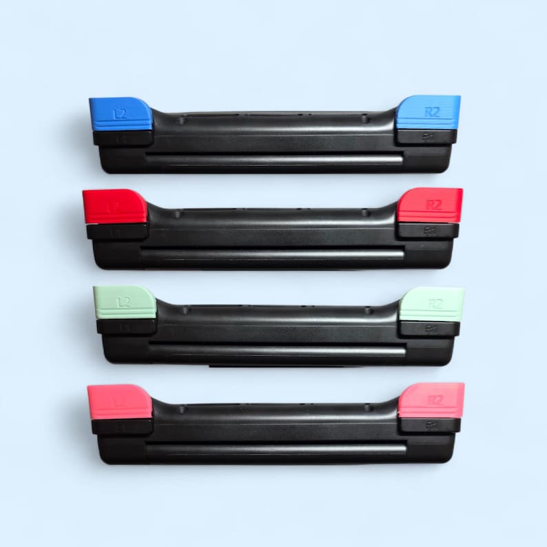May include: Four black controller trigger assemblies arranged vertically. Each unit features a black base with L2 and R2 buttons in distinct colors: blue, red, light green, and pink. The L2 and R2 labels are clearly embossed on the top buttons.