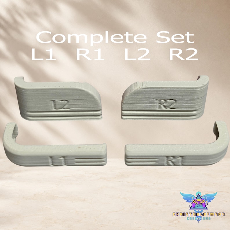 May include: A complete set of four light gray 3D-printed controller shoulder buttons labeled L1, R1, L2, and R2. The components feature a textured surface with embossed lettering and curved edges, designed for gaming controller customization and replacement.