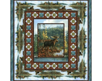 May include: A framed print of a moose standing in a forest by a lake. The print is surrounded by a blue and brown patterned frame.