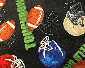 May include: A black fabric with a green and white "TOUCHDOWN" text repeated. The fabric is decorated with footballs, helmets, and football play diagrams.
