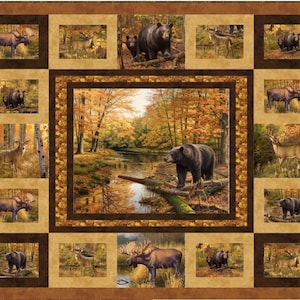 Könnte beinhalten: Ein Stoffquilt mit einem zentralen Bild eines Bären an einem Fluss in einem Herbstwald. Kleinere rechteckige Bilder von Bären, Hirschen und Elchen in einem Wald umgeben das zentrale Bild. Der Quilt hat einen braunen Rand.