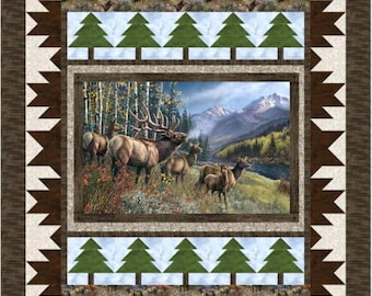 May include: A rectangular quilt featuring a central panel of elk in a mountain landscape, framed by borders of green pine tree silhouettes, a repeating elk pattern, and a dark brown sawtooth edge on a cream-colored background.