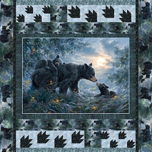 May include: A quilted blanket with a central image of a black bear family in a forest, framed by a border with bear paw prints and bear illustrations. The quilt has a blue and green colour scheme.